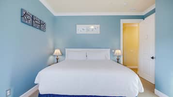 Un dormitorio con una cama grande, dos lámparas de noche, una obra de arte en la pared y una puerta que da a otra habitación.
