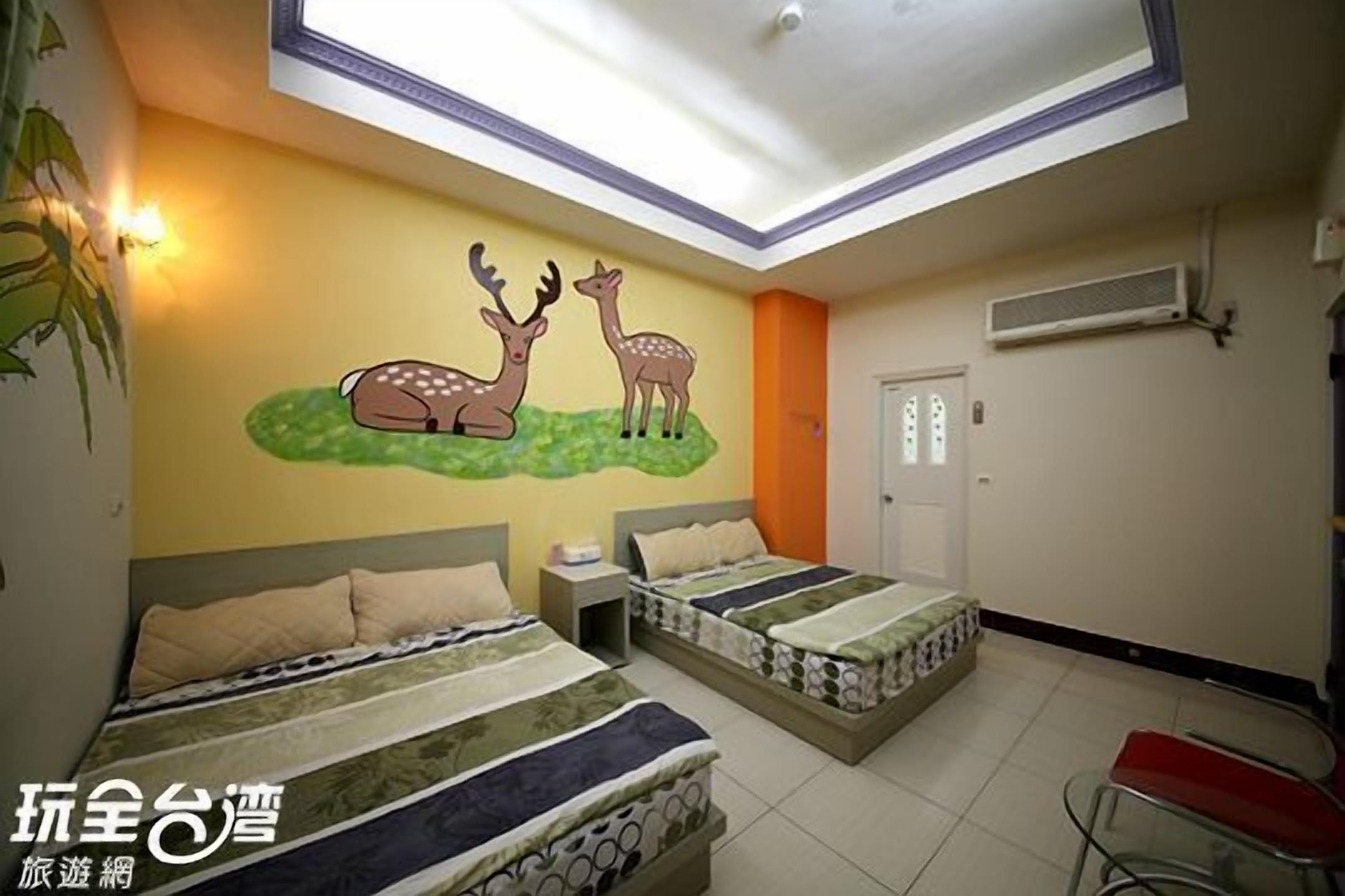 A hotel room with two beds, a wall mural of deer, a skylight, and a red chair.