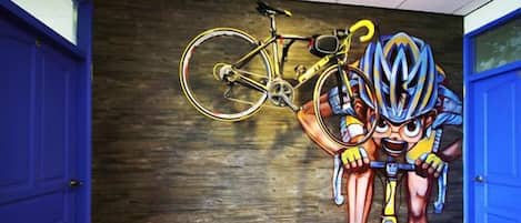 A mural of a cyclist with a bicycle on a wooden wall.