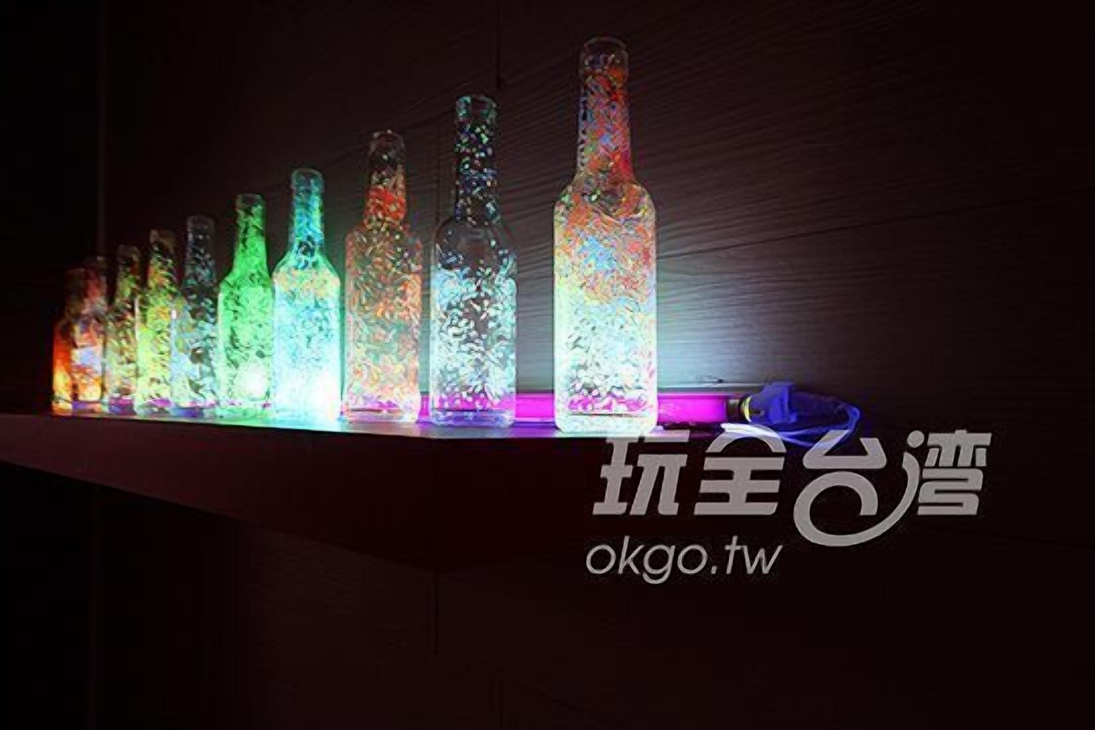 Una hilera de botellas iluminadas sobre un fondo oscuro.