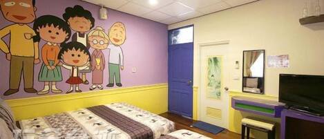 Una habitación con cama, televisión, puerta y pared decorada con personajes de caricatura.