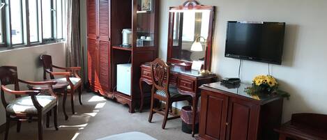 A hotel room with a bed, a desk with a lamp, a television, and a wardrobe.