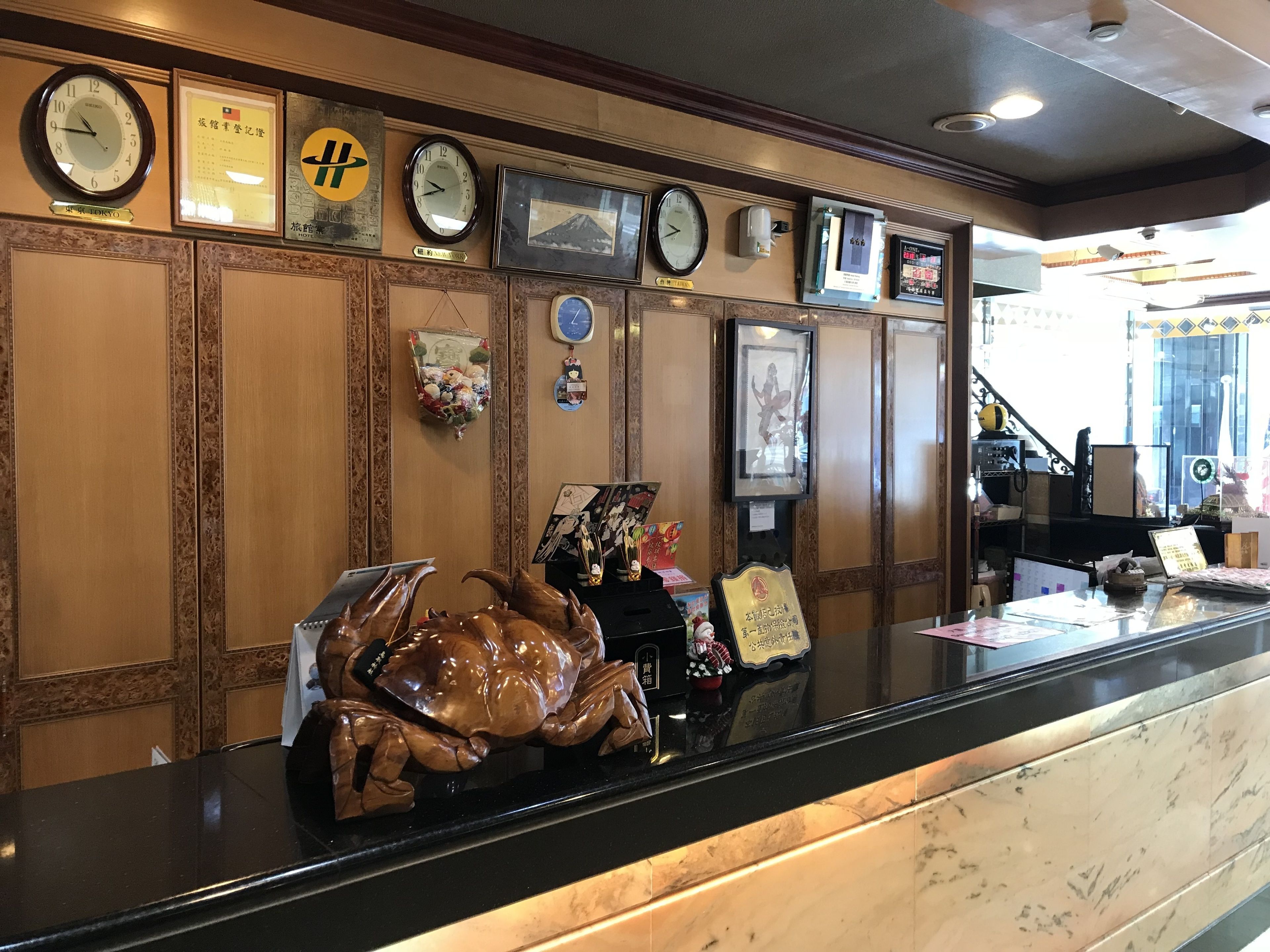 Un mostrador de recepción con relojes, cuadros enmarcados y una estatua decorativa de cangrejo.