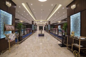 A spacious lobby with a marble floor, decorative lighting, and potted plants. - Golden Bujari Al Khobar Hotel (Al Khobar)