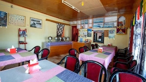 A dining area with tables covered in checkered tablecloths, chairs, and a counter with a menu.