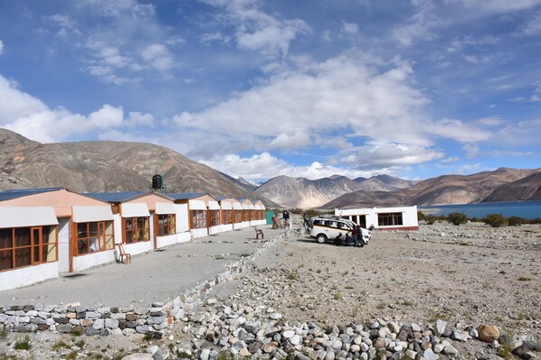 A row of white buildings with large windows and a white van parked in front.