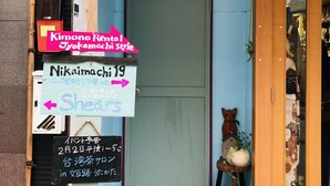A storefront with various signs indicating different services and directions. - Kimono Inn Utakata - Hostel (Himeji)