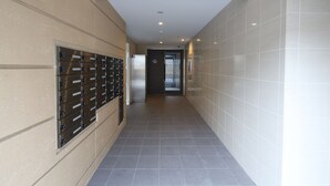 A hallway with a row of metal lockers on the left and a tiled wall on the right.