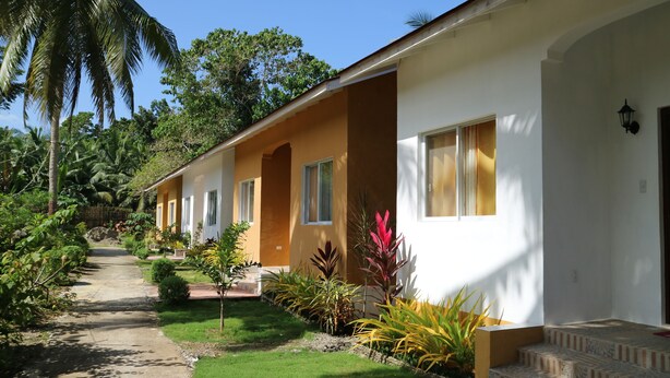 A two-story building with a garden pathway leading to the entrance. - Celvis Vacation Cottages (Panglao)