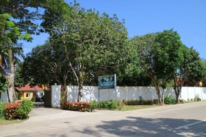 A gated entrance with a signboard, surrounded by trees and a clear sky. - Celvis Vacation Cottages (Panglao)