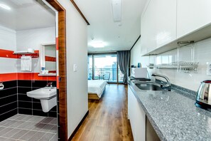 A modern hotel room with a bathroom, kitchenette, and a balcony with a view. - Rejina Pension (Seogwipo)