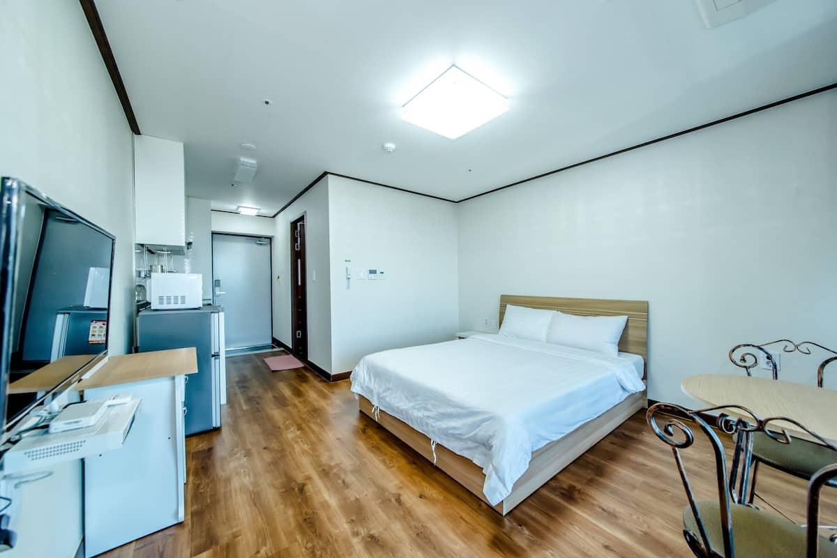 Een hotelkamer met een bed, een bureau met computer, een kleine kitchenette en een eethoek met tafel en stoelen.
