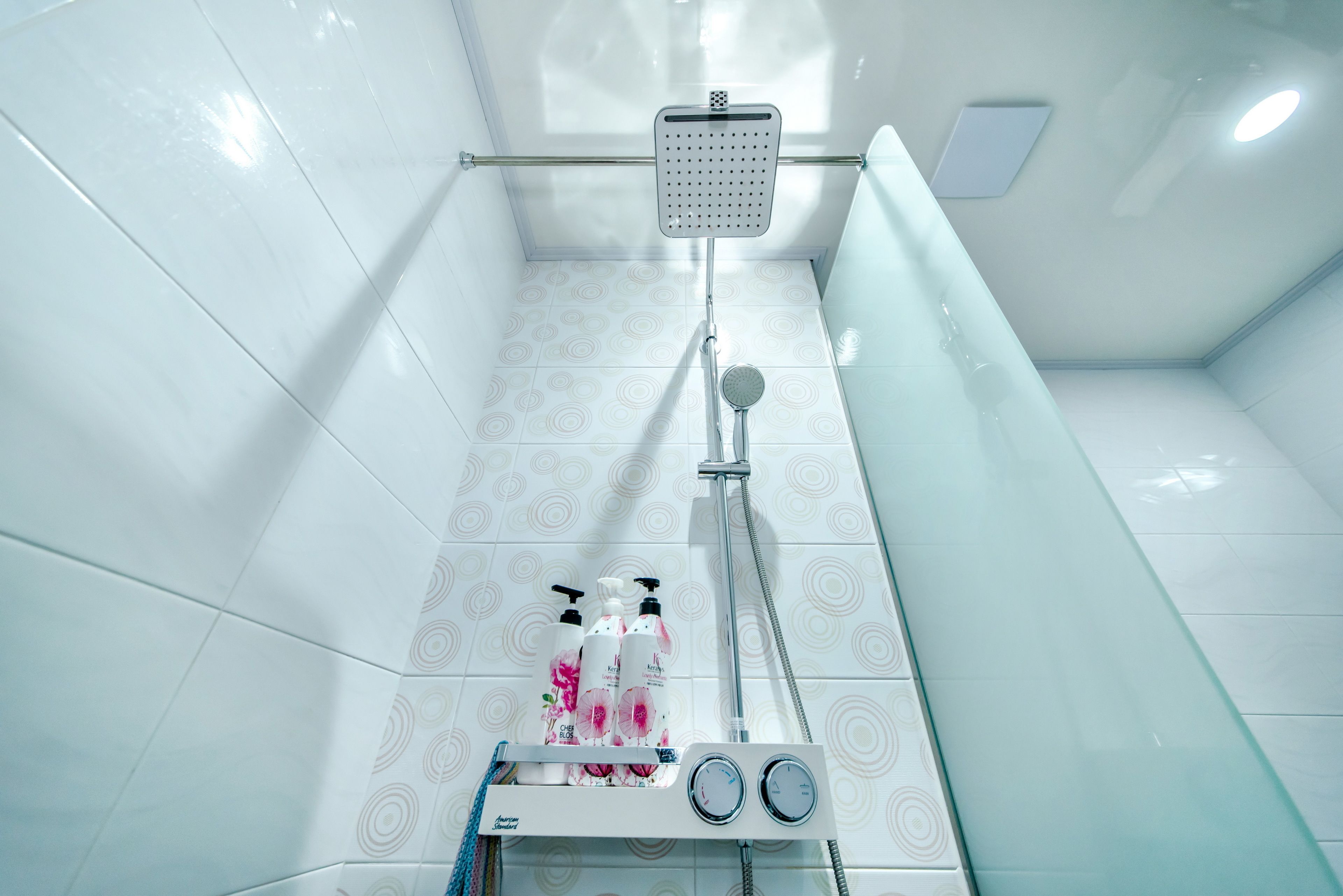 A modern shower area with a handheld showerhead, a wall-mounted faucet, and a glass partition.