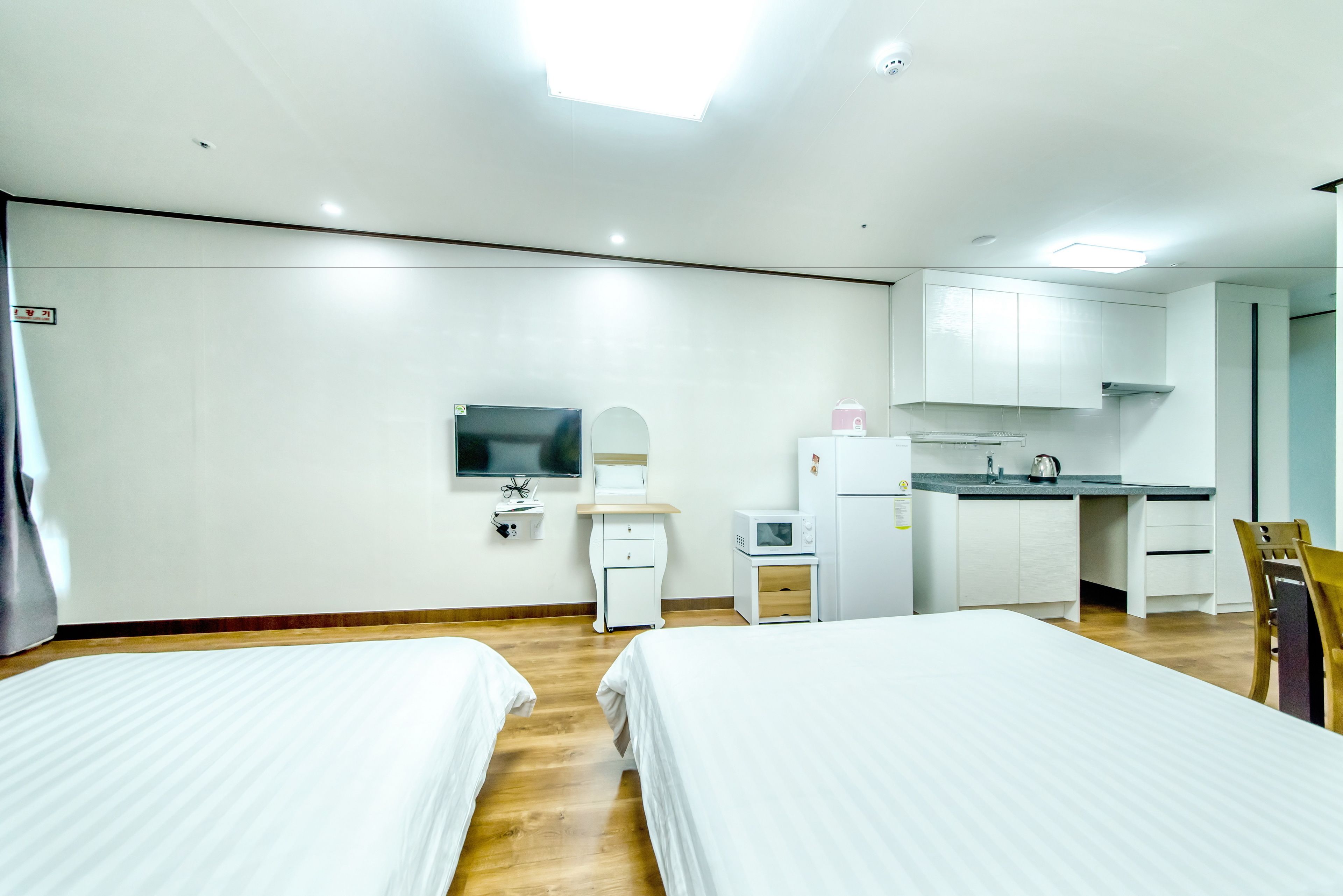 Une chambre d’hôtel avec deux lits, une petite kitchenette, un téléviseur à écran plat et un miroir.