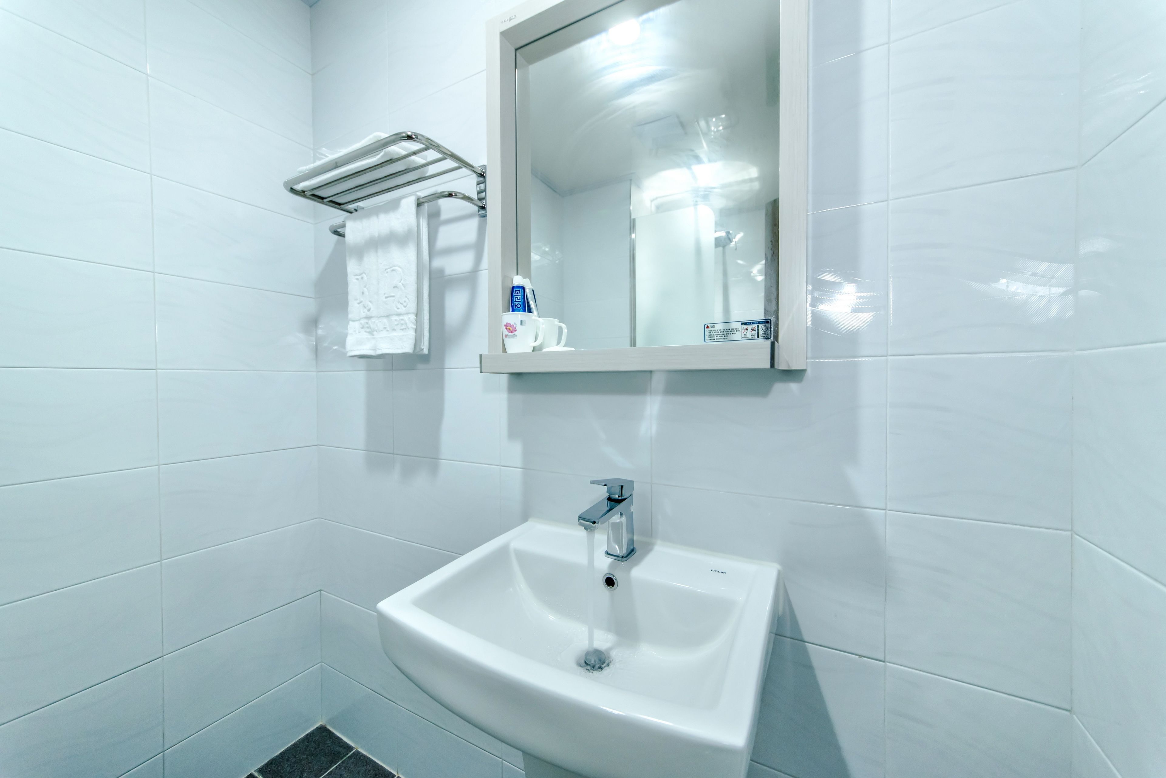 A bathroom with a white sink, a mirror, and a towel rack.