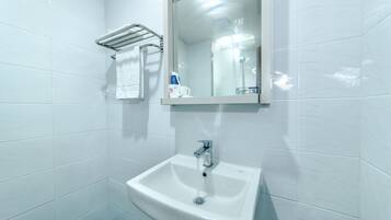A bathroom with a white sink, a mirror, and a towel rack.