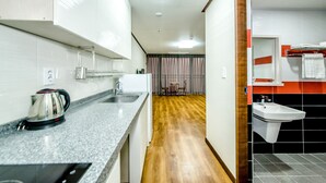 A modern kitchen with a kettle, sink, and wooden flooring. - Rejina Pension (Seogwipo)