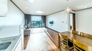 A modern hotel room with a kitchen, dining area, and a balcony with a view. - Rejina Pension (Seogwipo)