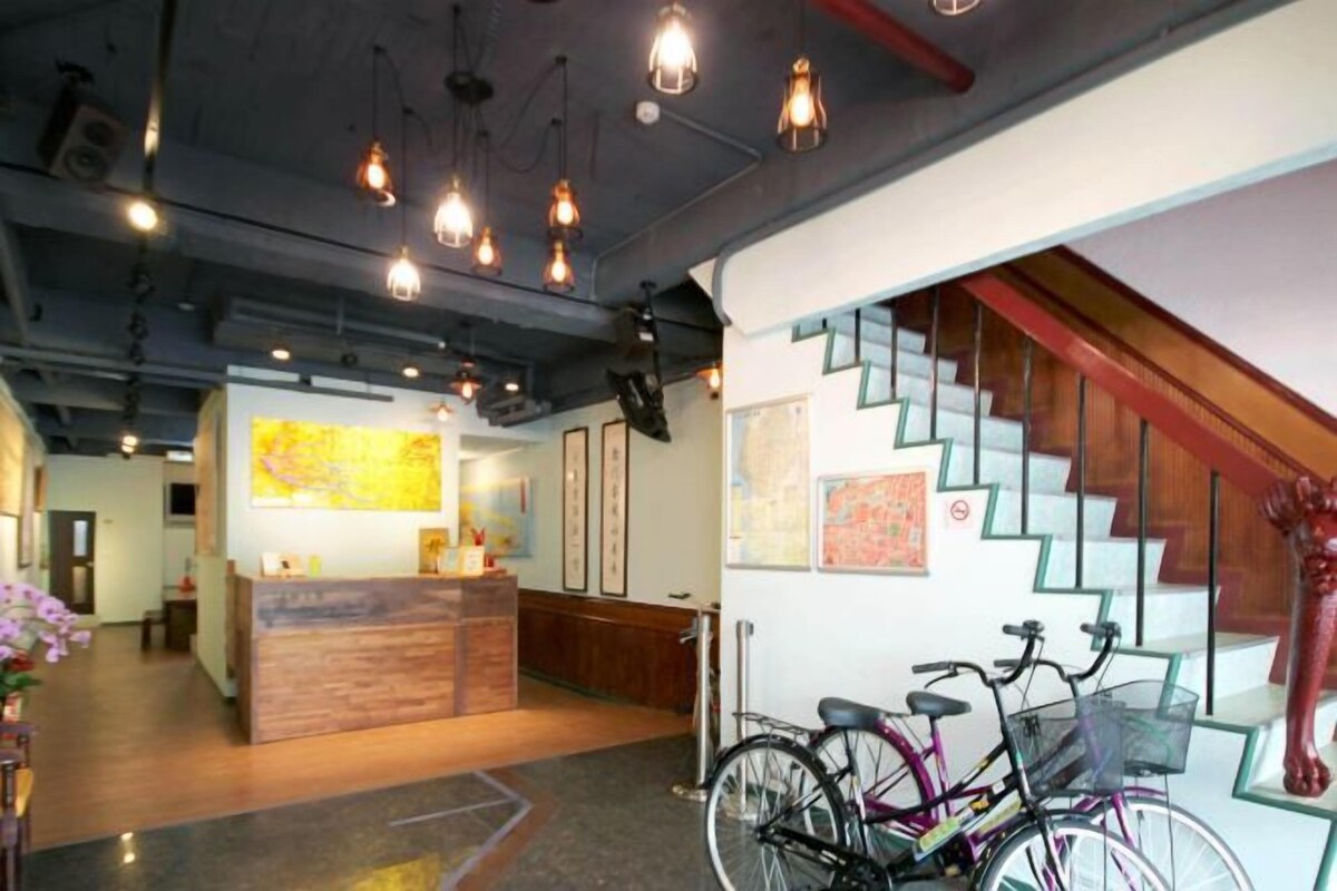 Zona de recepción con un mostrador de madera, una escalera y bicicletas.
