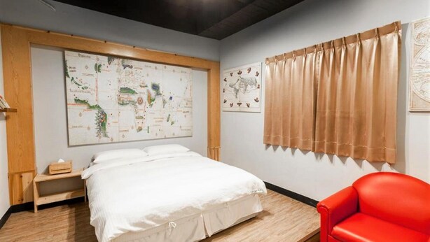 Un dormitorio con una cama grande, una silla roja y dos mapas en las paredes.