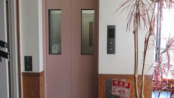 Puerta de ascensor rosa con letrero de extintor y pantalla digital.