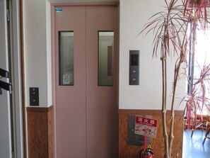 A pink elevator door with a fire extinguisher sign and a digital display. - Akitaya (Kamakura)