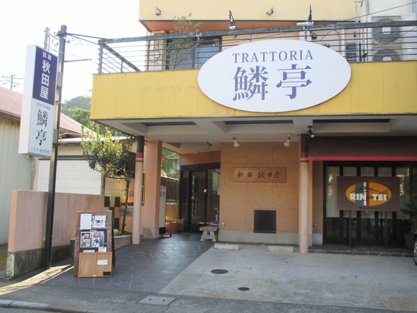 A building with a sign reading "TRATTORIA" and another sign with Japanese characters. - Akitaya (Kamakura)