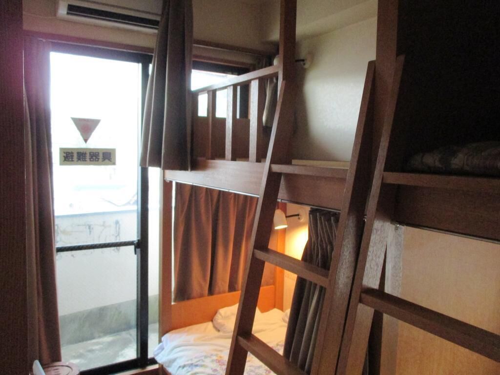 A bunk bed room with a window, curtains, and a sign in Japanese.