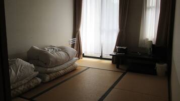 A hotel room with a bed, a desk, and a window with curtains.
