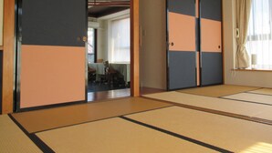 A traditional Japanese room with tatami flooring, sliding doors, and a view of a dining area. - Akitaya (Kamakura)