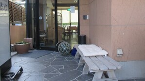 A wooden bench, a potted plant, and a glass door leading to an outdoor seating area. - Akitaya (Kamakura)