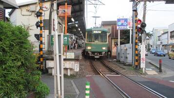 A train station platform with a green train approaching.