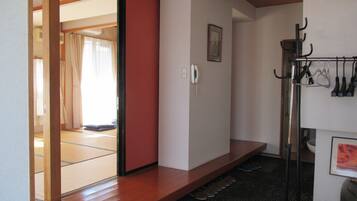 A room with tatami mat flooring, a wooden sliding door, a telephone, and a shoe rack.