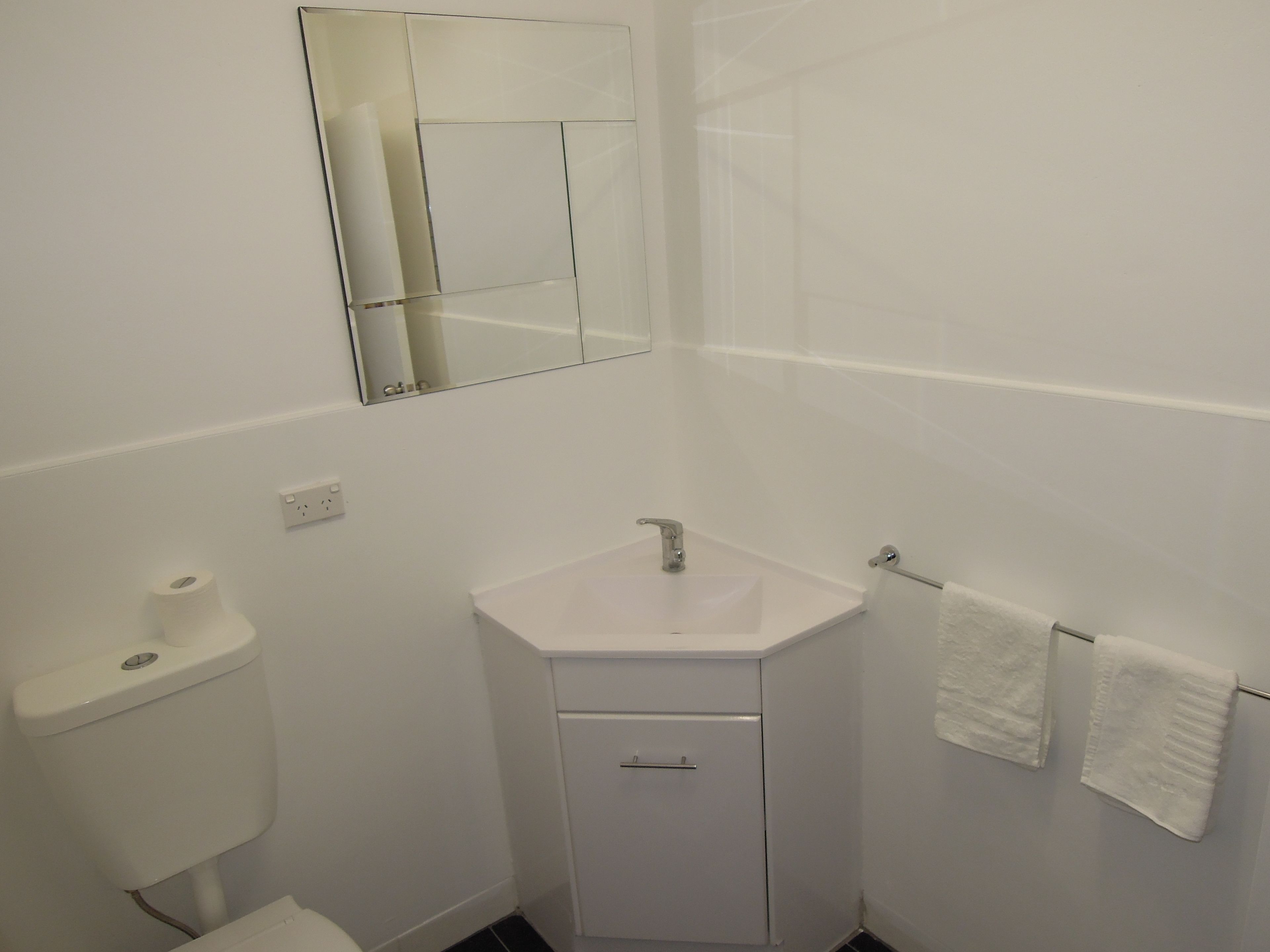 A small, white bathroom with a toilet, sink, and towel rack.