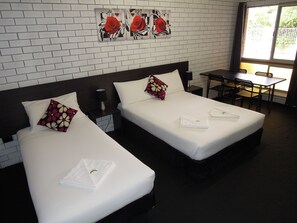 A hotel room with two beds, a desk, and a window. - Jackaroo Apartments (Moree)
