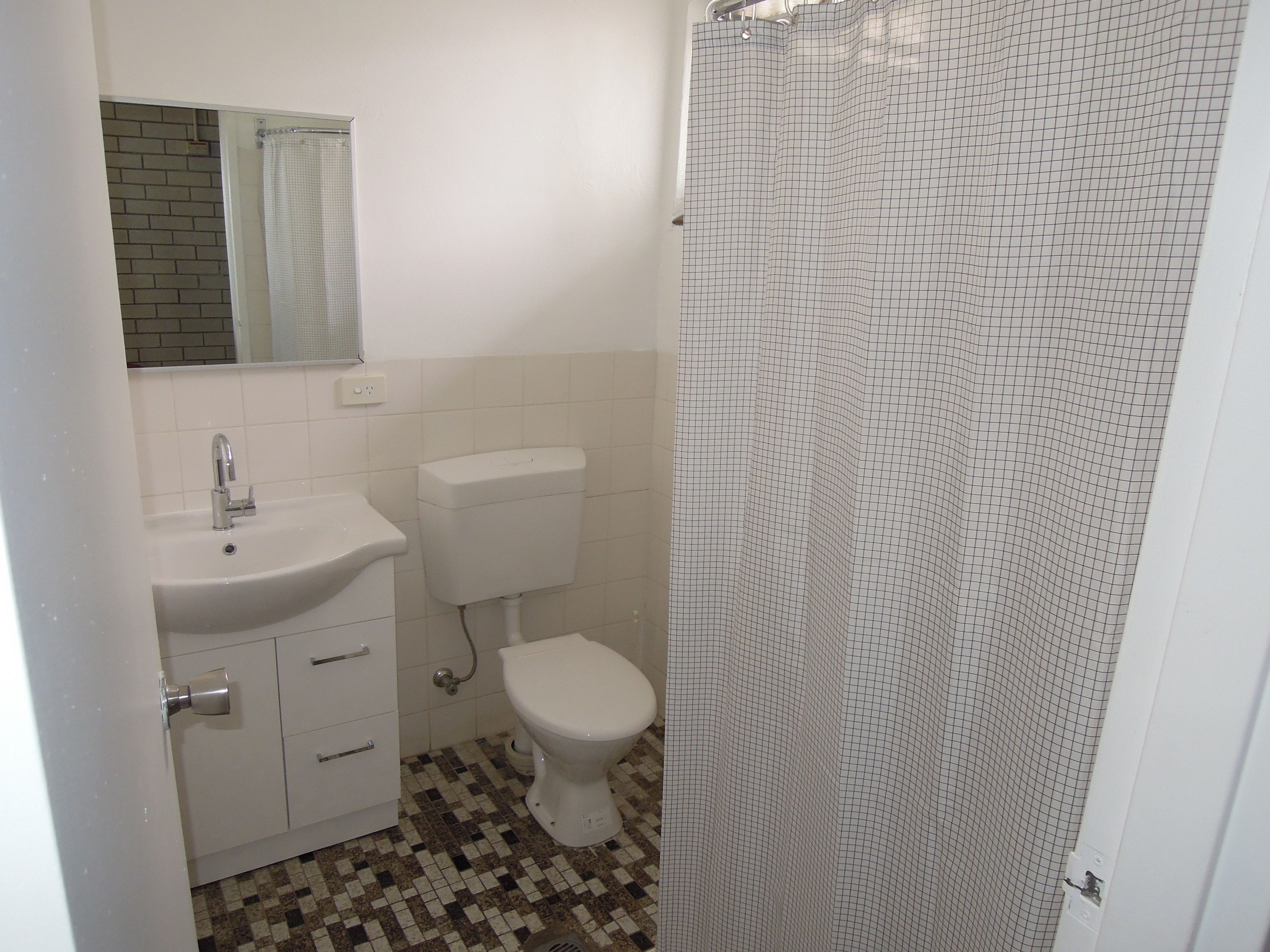 Un baño con lavamanos, inodoro y cortina de ducha blancos.