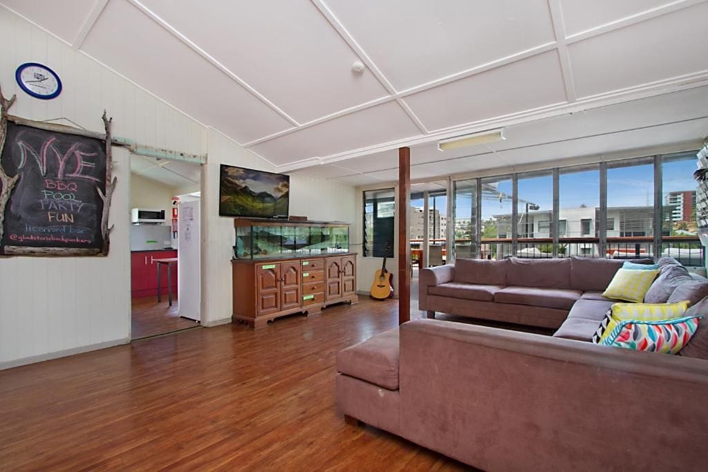 A modern living room with a large window, a fish tank, a couch, and a chalkboard with event details.