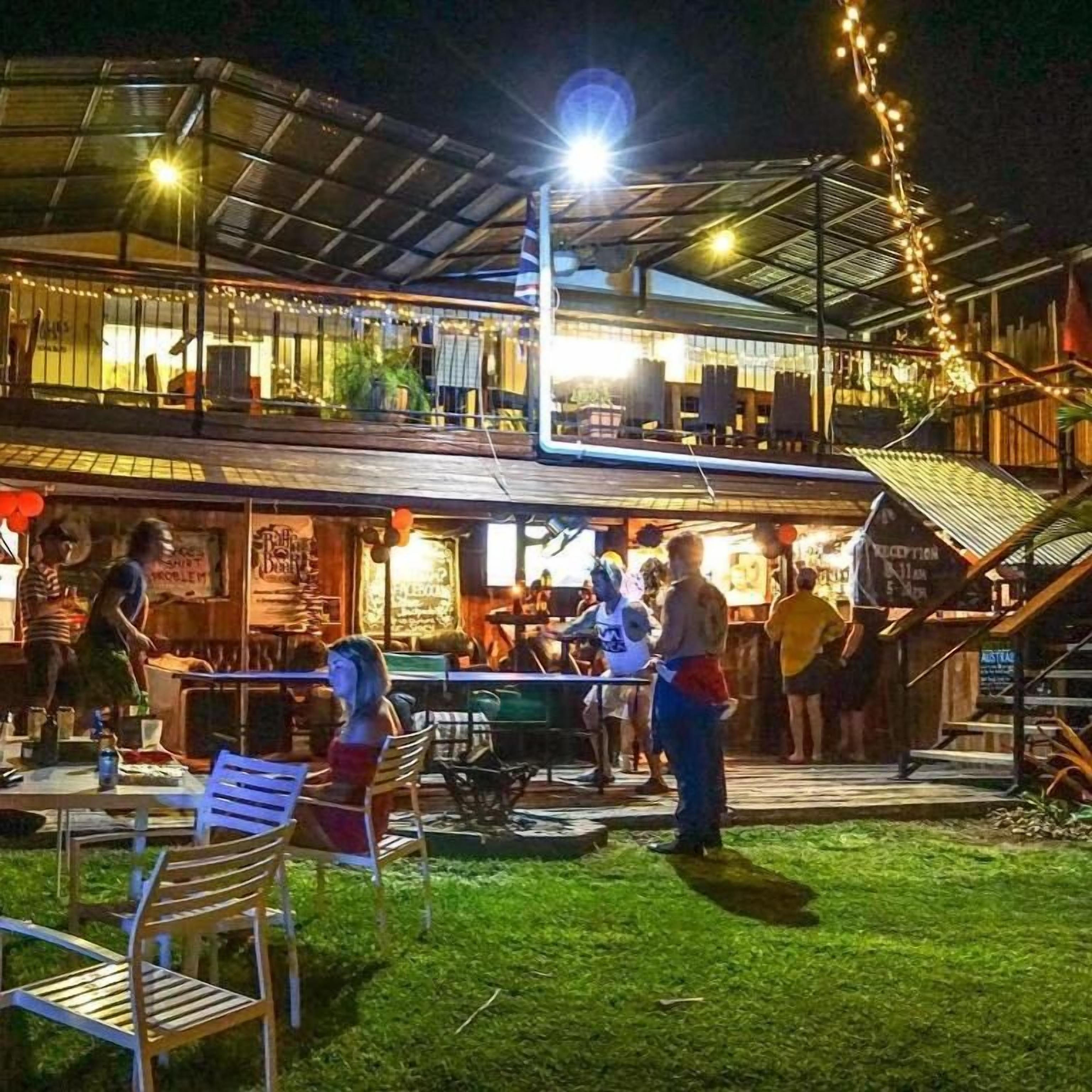 An outdoor dining area with tables and chairs, a covered seating area, and a staircase leading to an upper level.