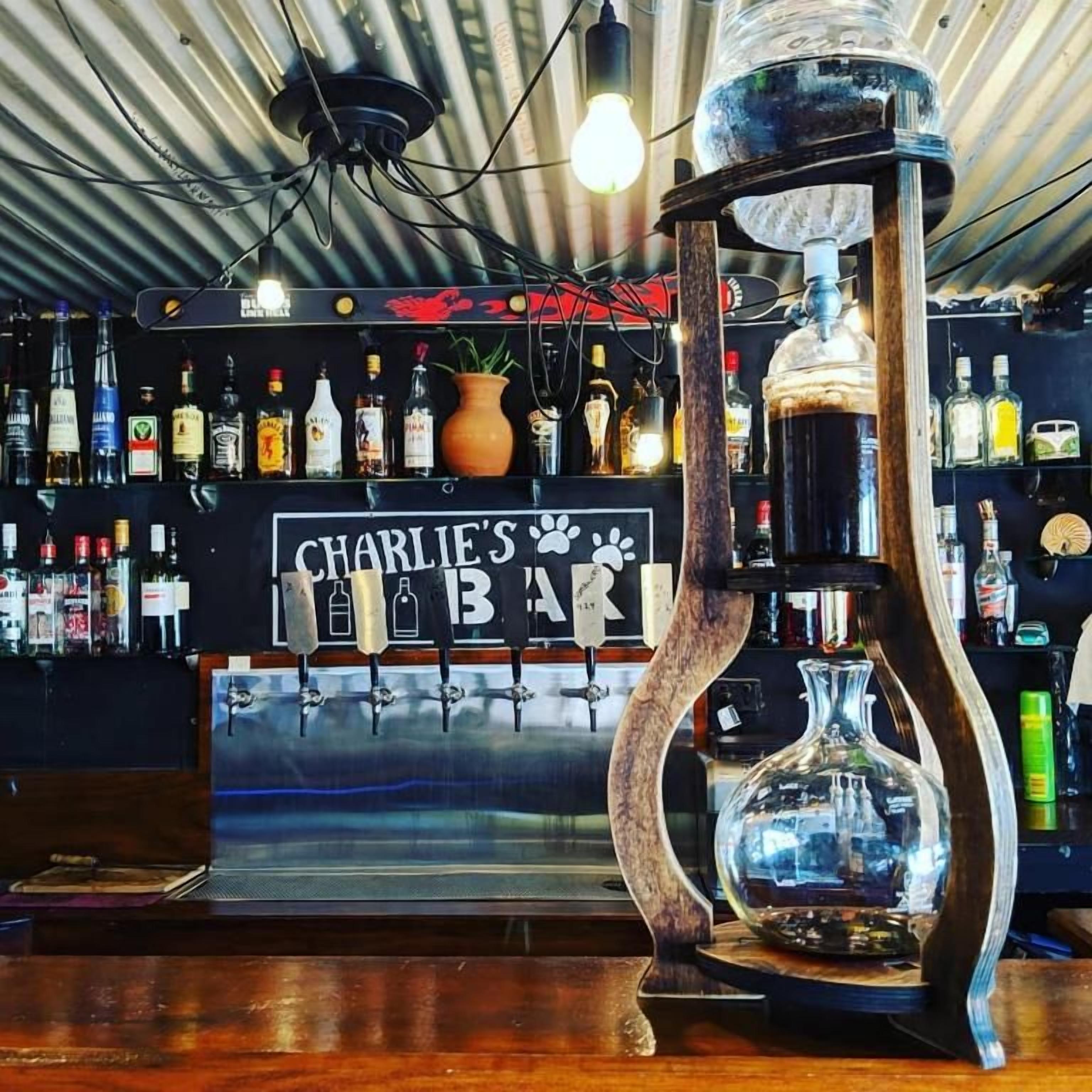 A bar with a sign reading 'CHARLIE'S BAR' and a variety of liquor bottles.
