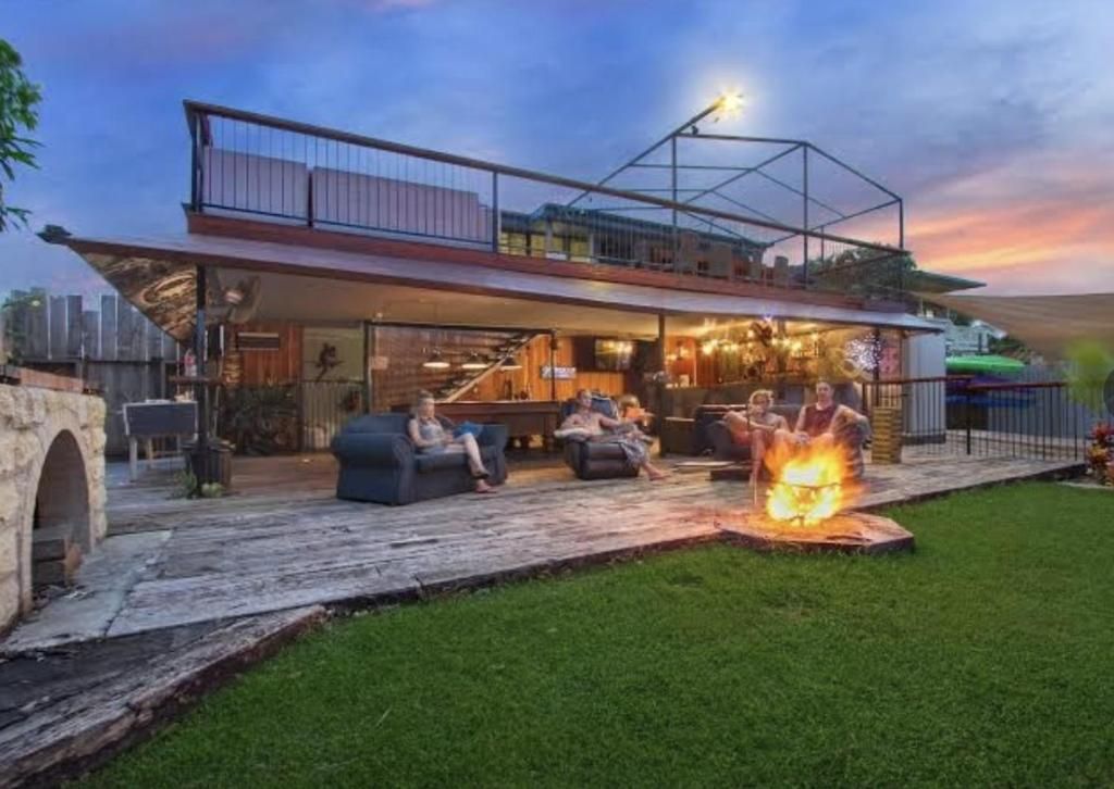 Una casa moderna con un espacio exterior cubierto, una fogata y un balcón con vistas al paisaje.