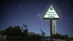A sign for Pineacres Holiday Park with a starry night sky in the background.