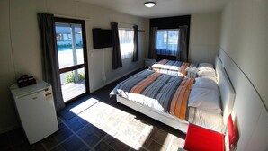 A room with two beds, a television, and a small refrigerator.