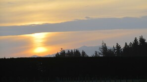 A sunset over a mountainous landscape with trees in the foreground.