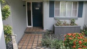 A house with a dark blue door, a small front porch with a tiled floor, and a window with blue shutters. - Vacation Villas at Subic Homes (Morong)