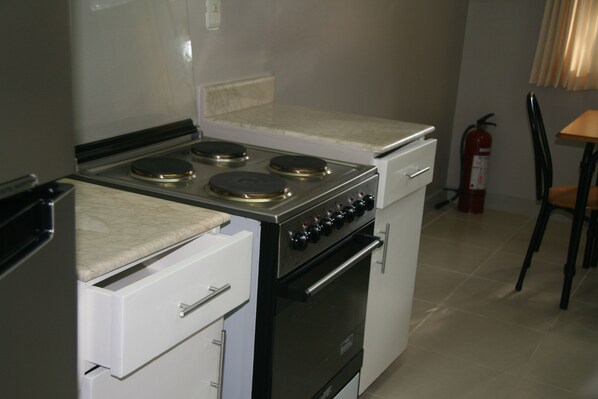 Una cocina compacta con estufa, horno y un pequeño comedor con una silla y una mesa.