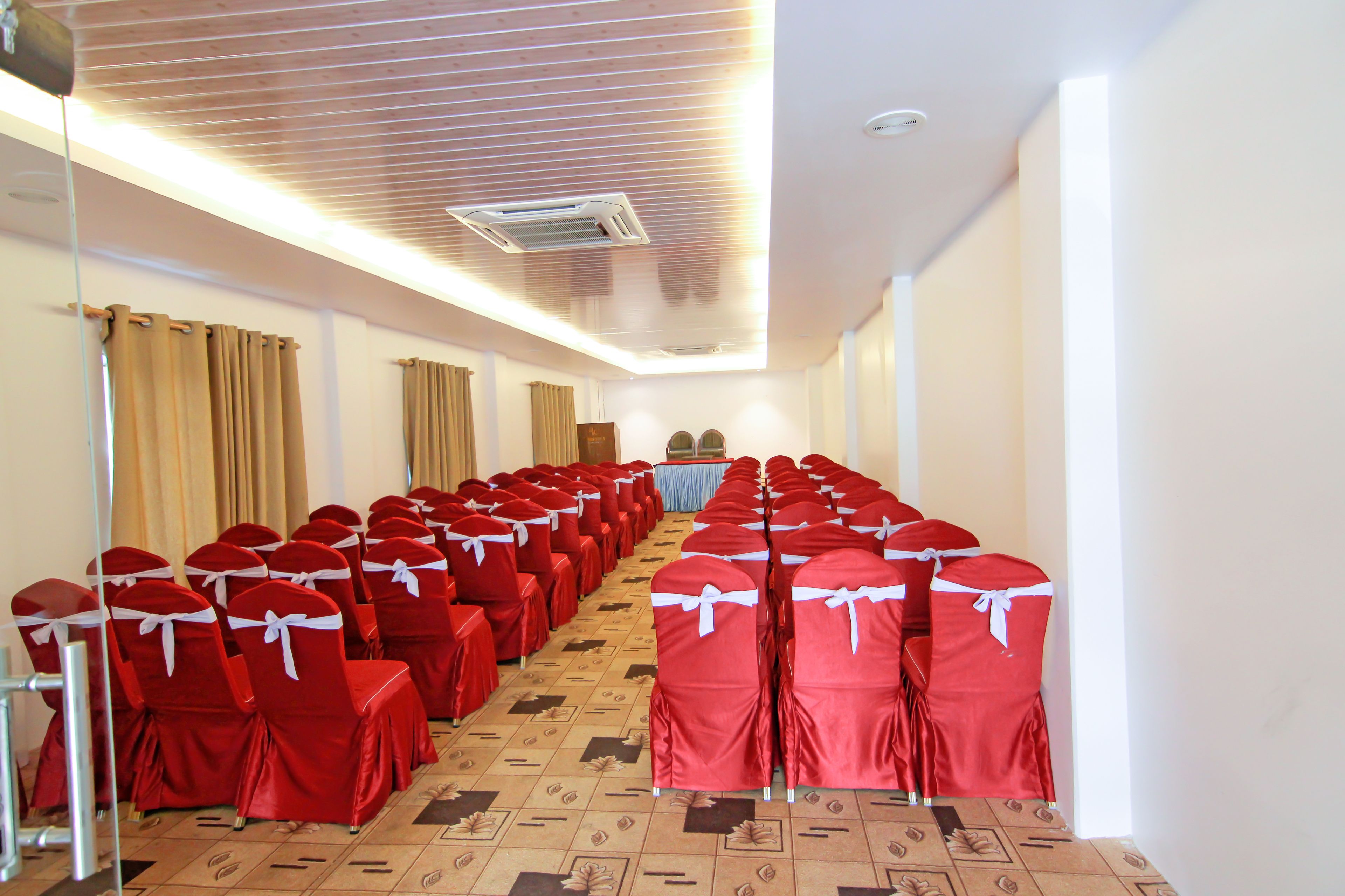 A conference room with rows of red chairs, a podium, and a carpeted floor.