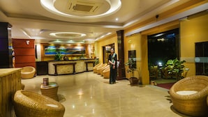 A hotel lobby with a reception desk, wicker furniture, and a large painting on the wall. - Kuti Resort and Spa (Pokhara)
