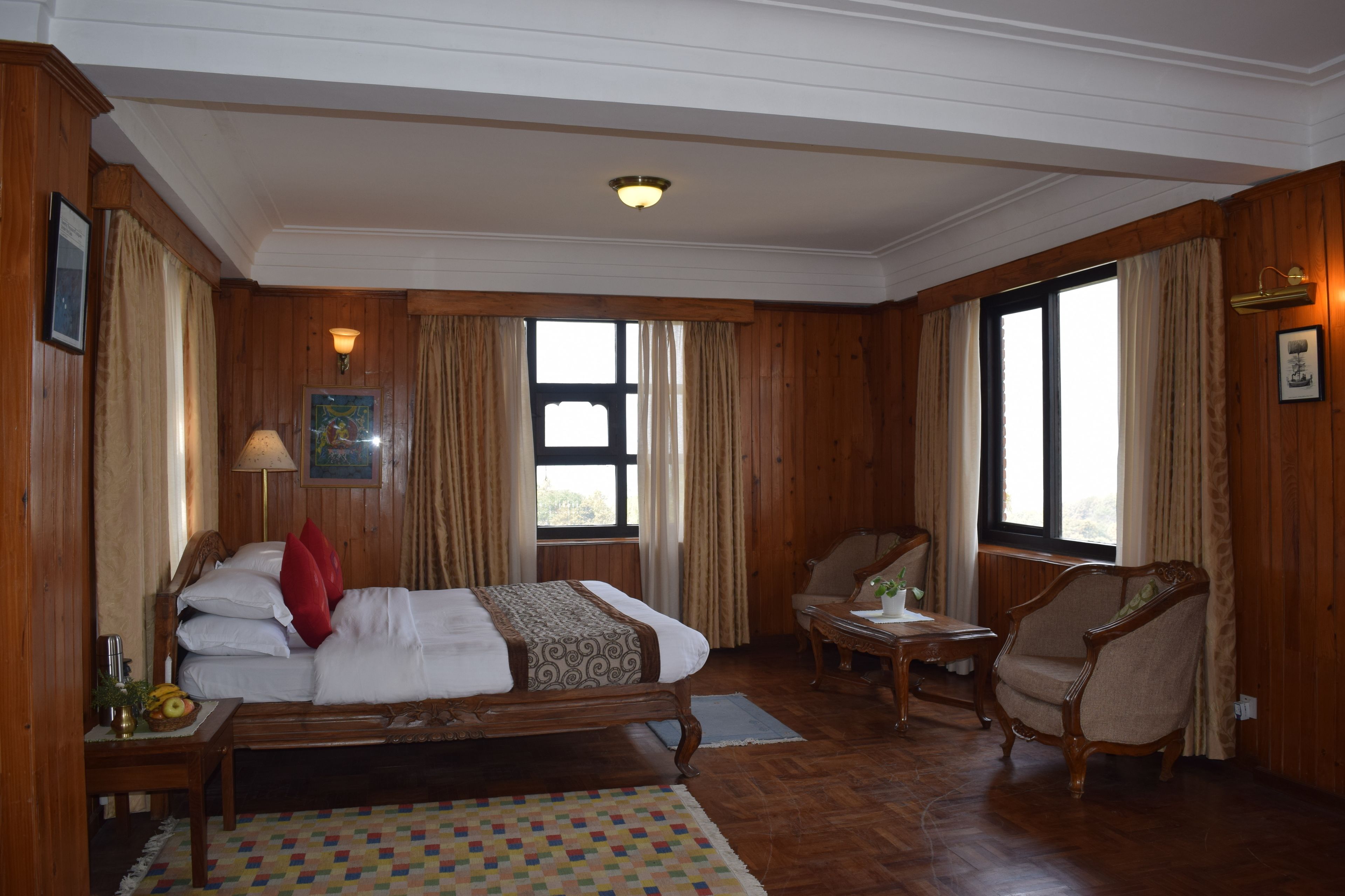 Quarto de hotel com uma cama grande, uma cadeira, uma mesa pequena e uma janela.