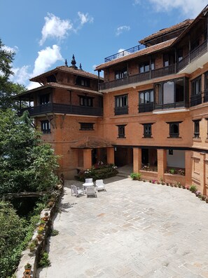 A courtyard with a traditional building featuring multiple balconies and a central seating area. - The Fort Resort (Baluwapati Deupur)
