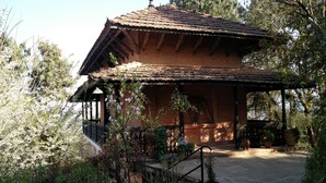 A traditional brick building with a tiled roof, surrounded by lush greenery and a stone pathway leading to the entrance. - The Fort Resort (Baluwapati Deupur)